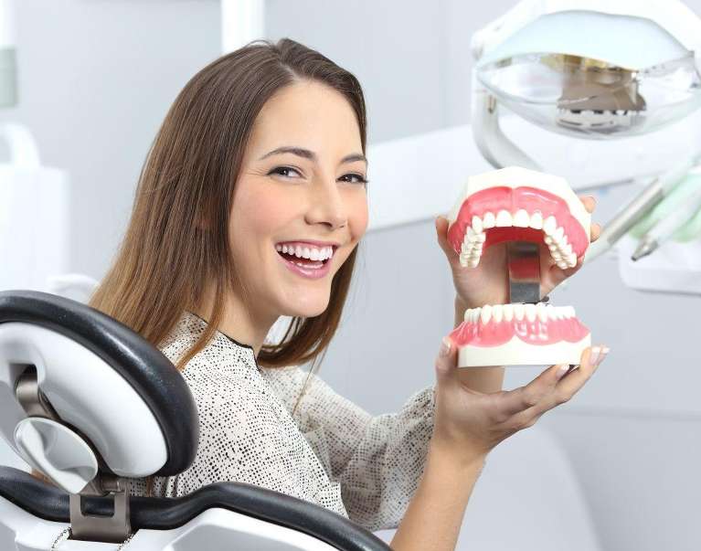 An image showing a woman holding a depiction of teeth in Wahroonga, NWS