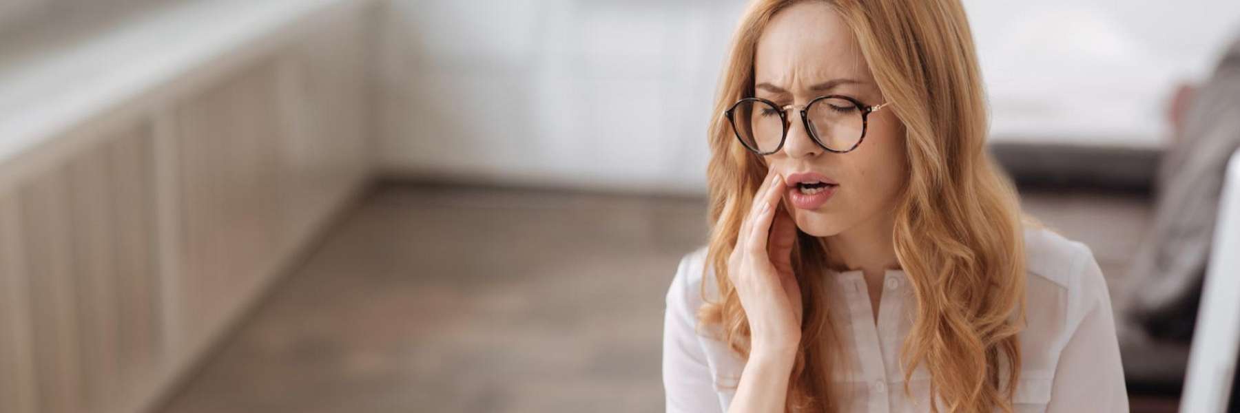 A woman holding her mouth in pain waiting to get an emergency dentistry in Wahroonga, NWS